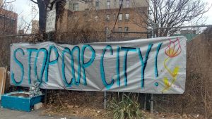 A banner hanging on a fence surrounding the garden that reads "Stop Cop City!"